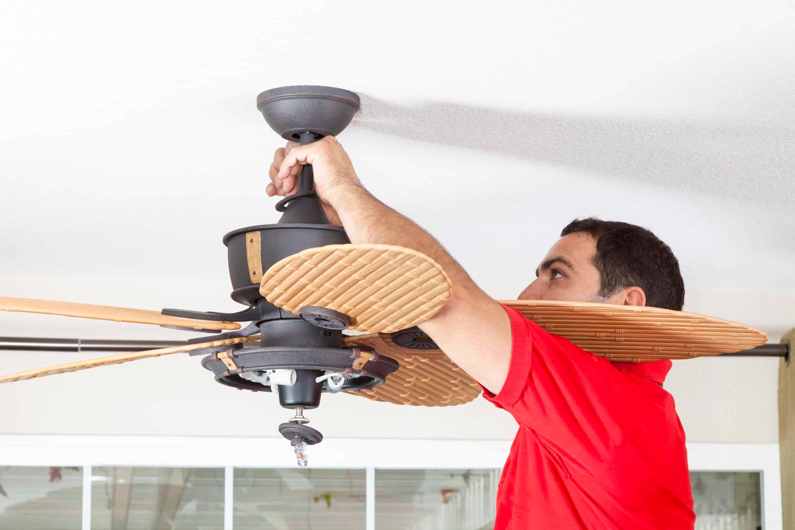 Handy Hive Pros technician installing a modern ceiling fan in a home, ensuring proper wiring and secure mounting for optimal air circulation and energy efficiency.