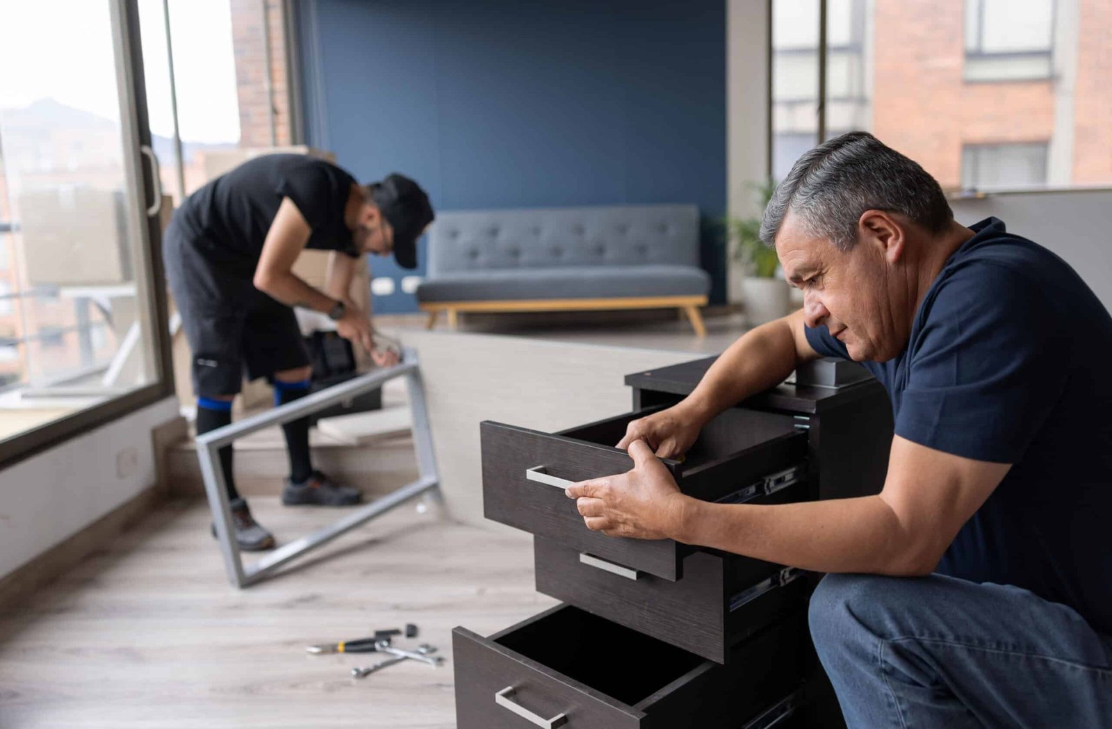 Two Handy Hive Pros technicians assembling furniture in a modern apartment. Professional furniture assembly services in Tampa, FL.