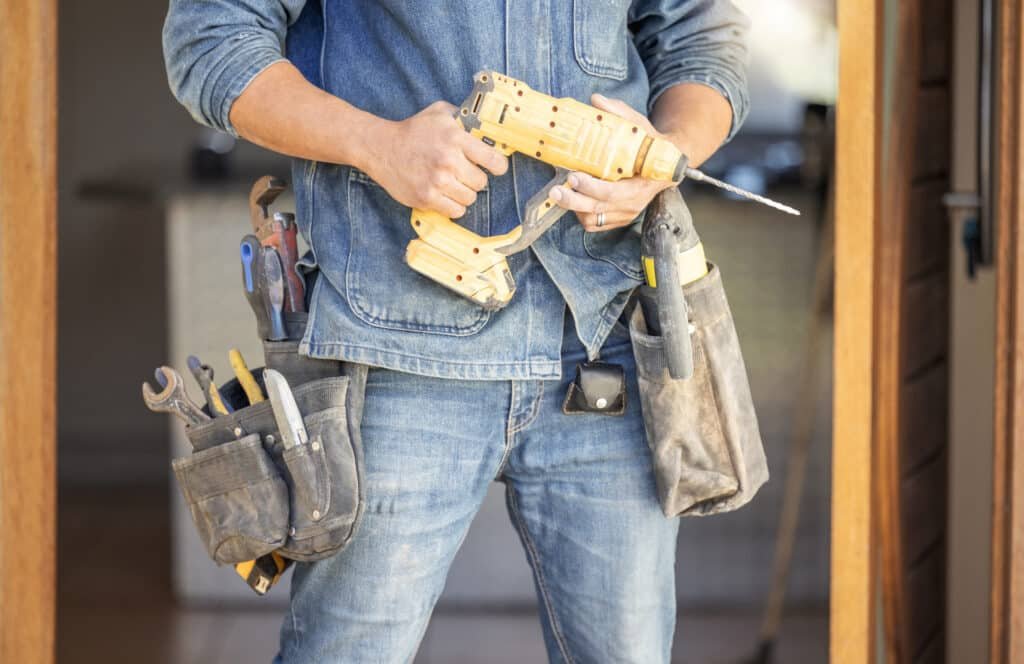 Handy Hive Pros handyman holding a power drill and tool belt, ready for home repair, renovation, and improvement services.