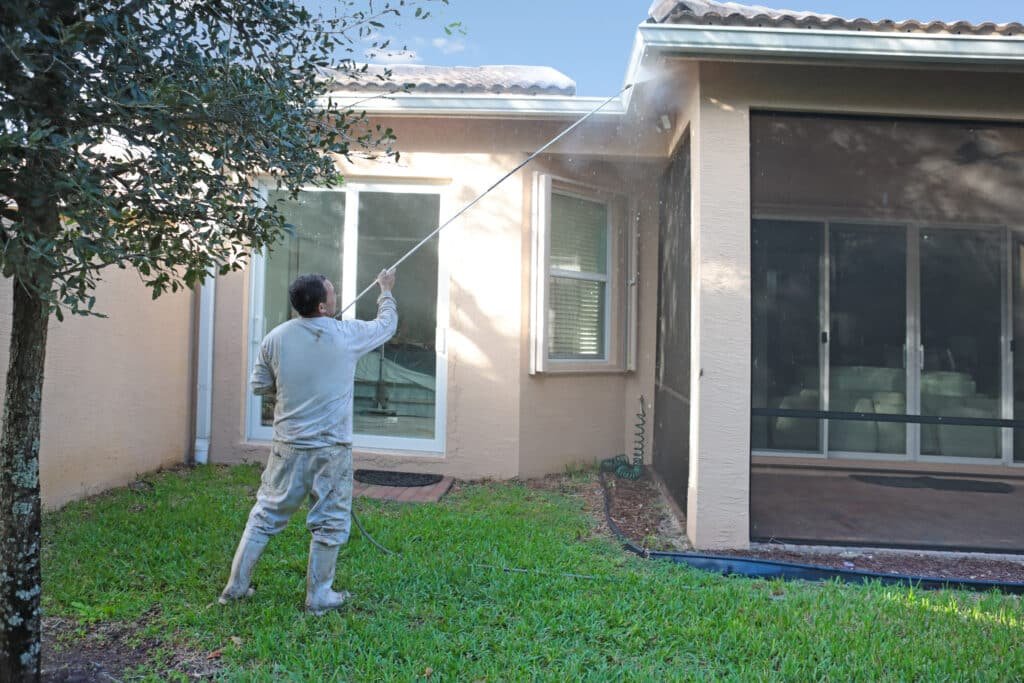 Professional pressure washing service cleaning the exterior of a one-story home – Handy Hive Pros house washing services.