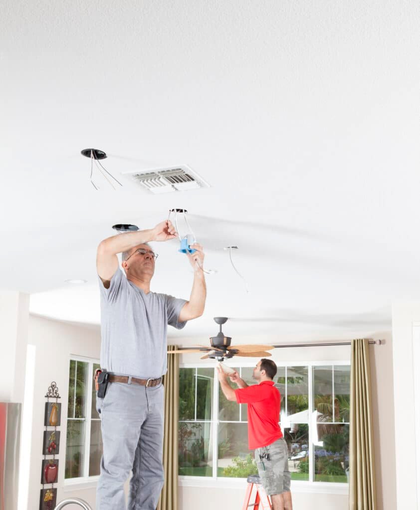 Professional electricians installing recessed ceiling lights and a ceiling fan in a home – Handy Hive Pros lighting and fan installation services.