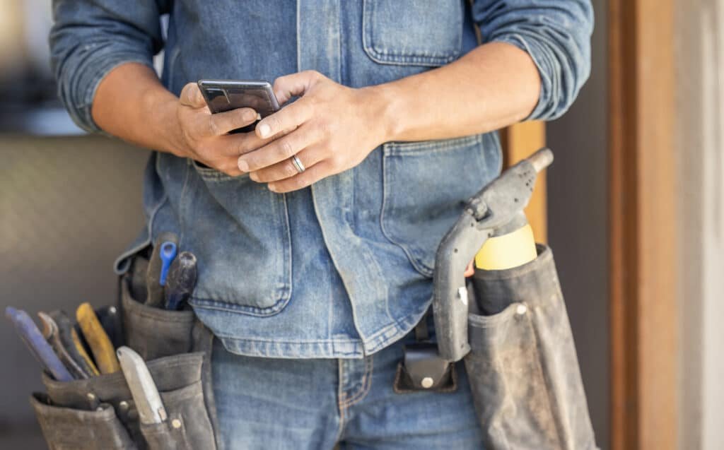 Handyman using a smartphone to check job instructions, schedule, or communicate with a customer – Handy Hive Pros.