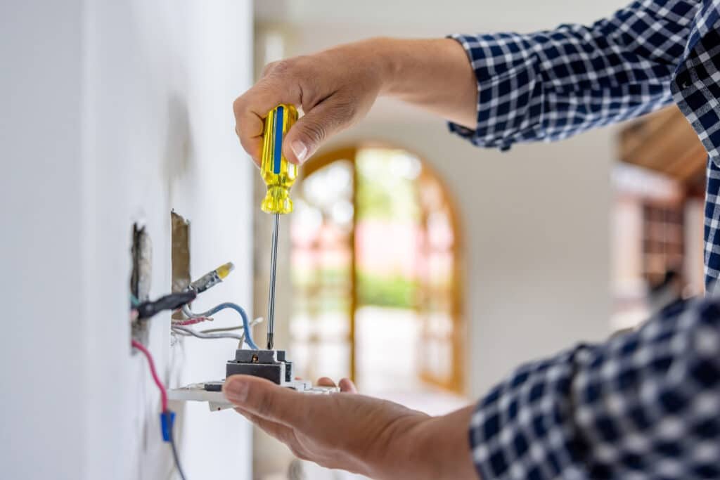 Electrician installing a power outlet during a home remodeling project – Handy Hive Pros electrical installation and maintenance services.